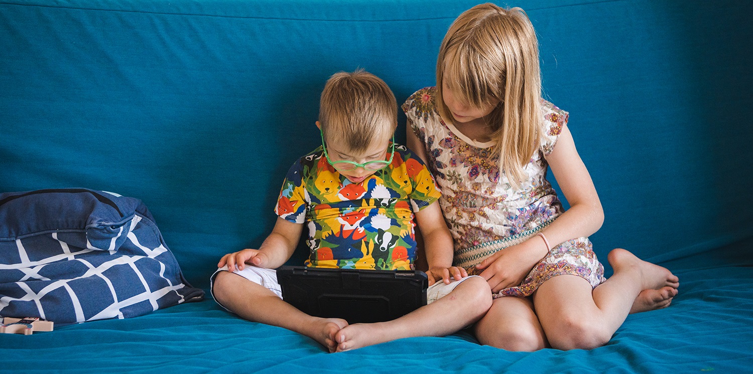 Two children on a sofa looking at a tablet